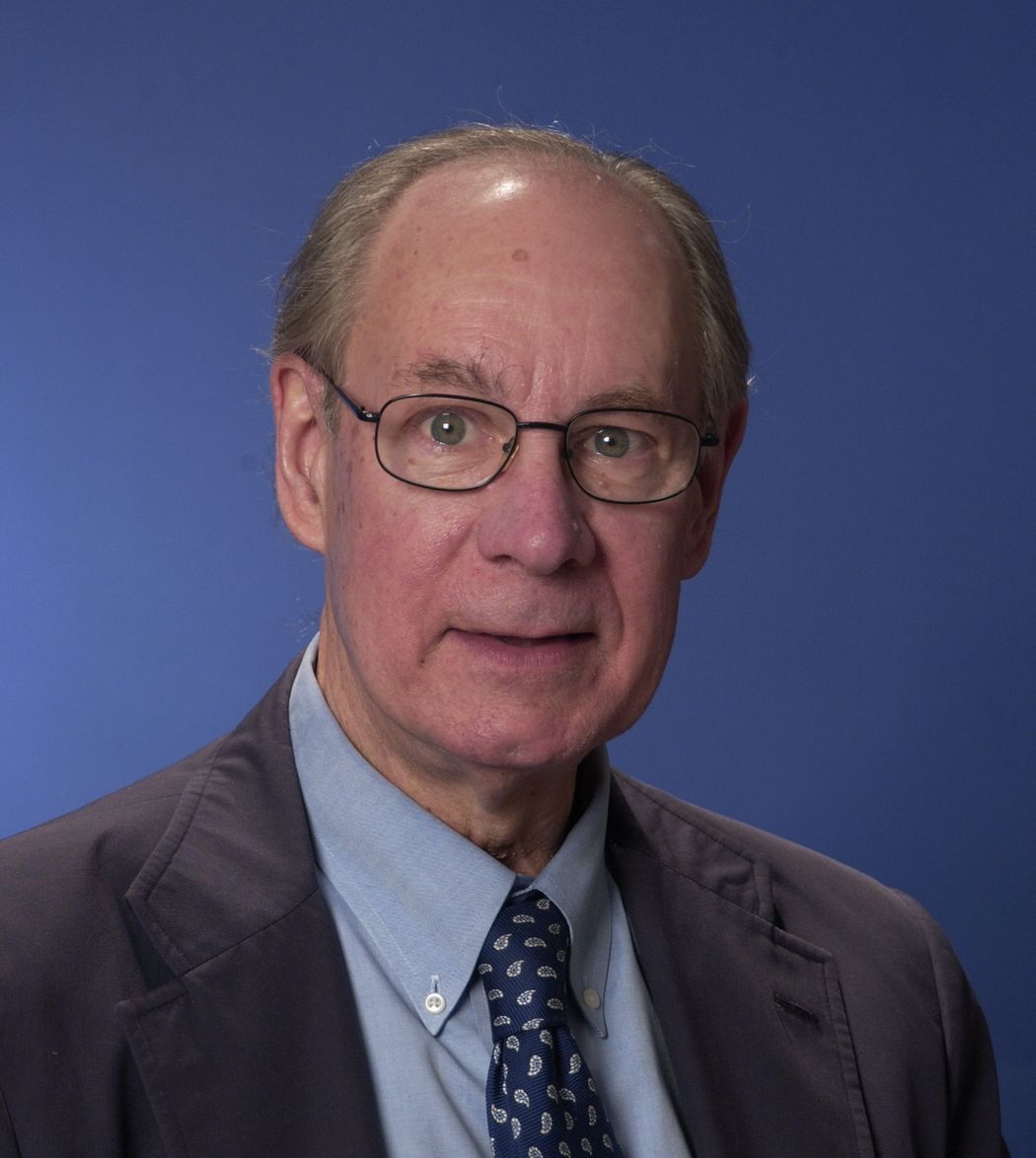Photo of Breakthrough Prize laureate, endocrinologist Joel Habener against a blue background. He wears a blue shirt, blue tie, and black blazer.