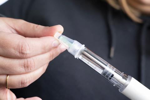 Hands holding a GLP-1 injector