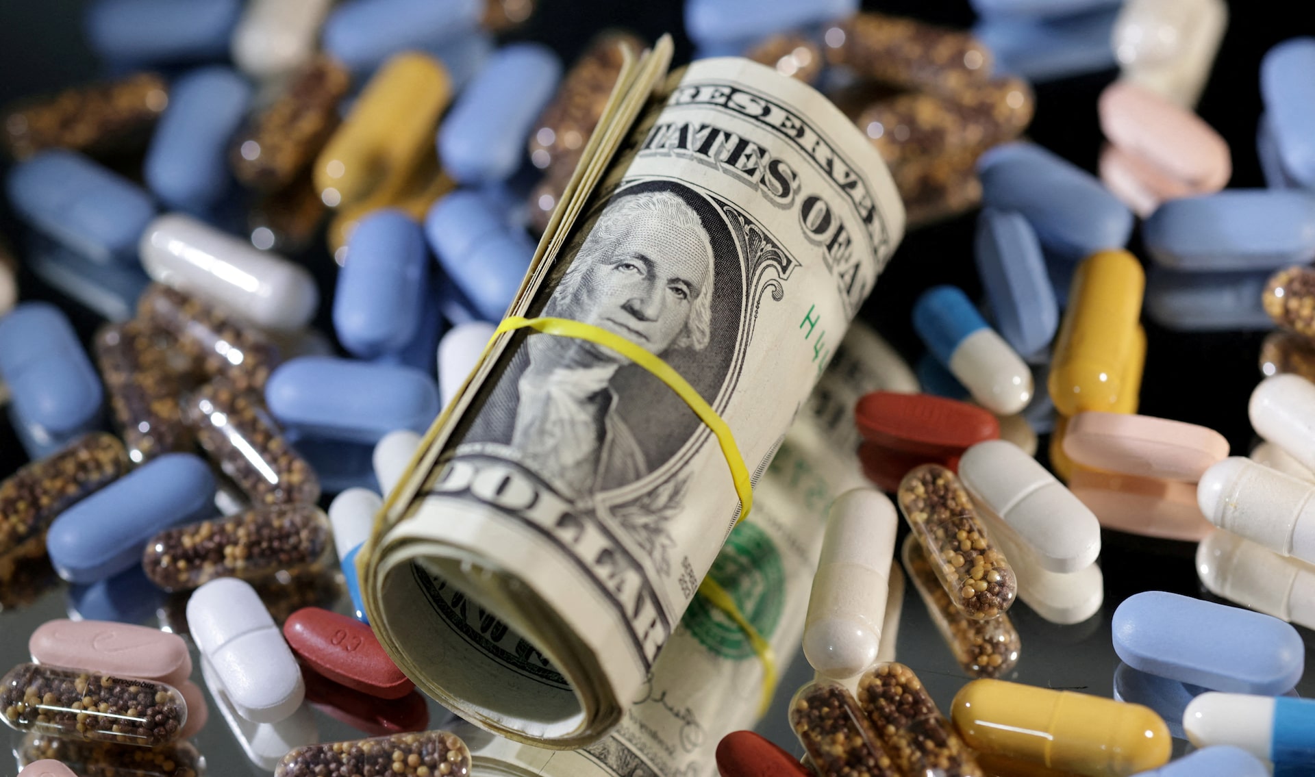 Illustration shows U.S. dollar banknotes and medicines