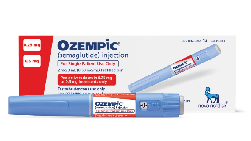 This image shows an Ozempic pen laying flat in front of the packaging.