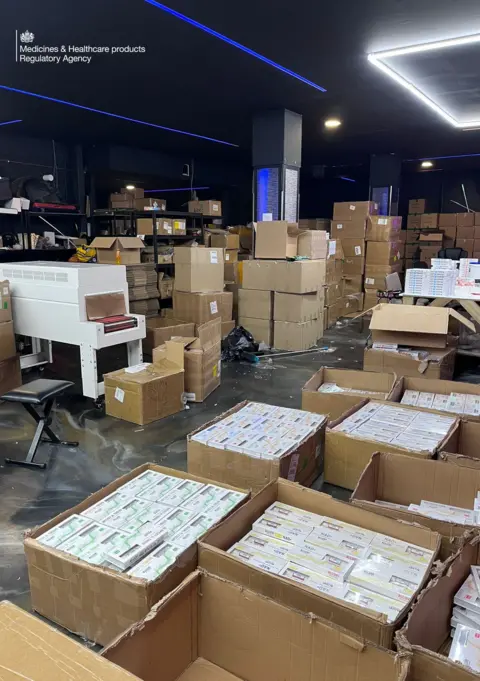 MHRA An interior shot of a factory showing boxes of drugs. Cardboard boxes are open showing unlicensed medication in little white boxes