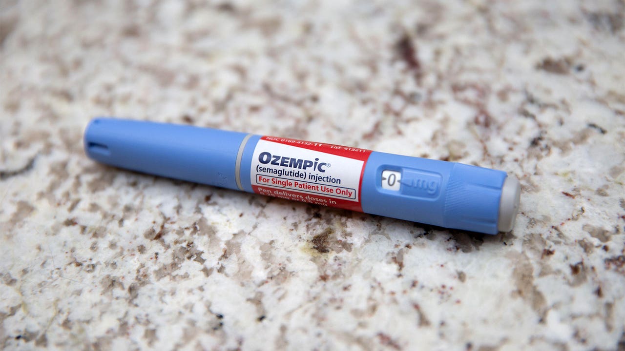 A photo of an Ozempic injection pen laying on a marble countertop.